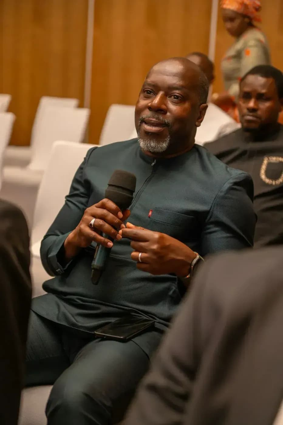A seated attendee speaks into the microphone
