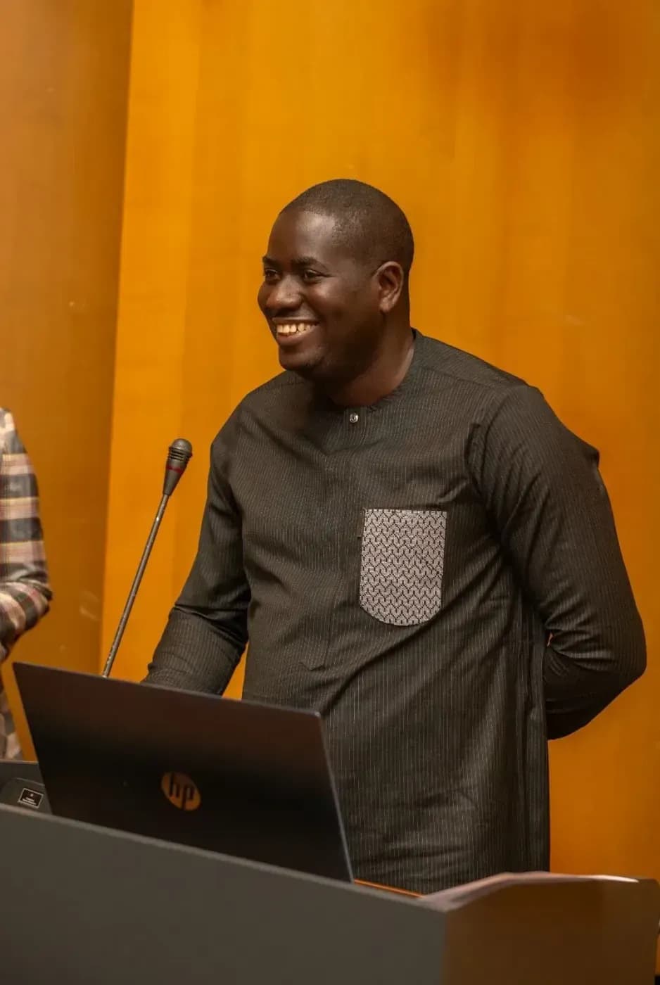A smiling speaker addresses the room from the lectern