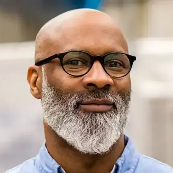 Un homme chauve avec une barbe et des lunettes sourit